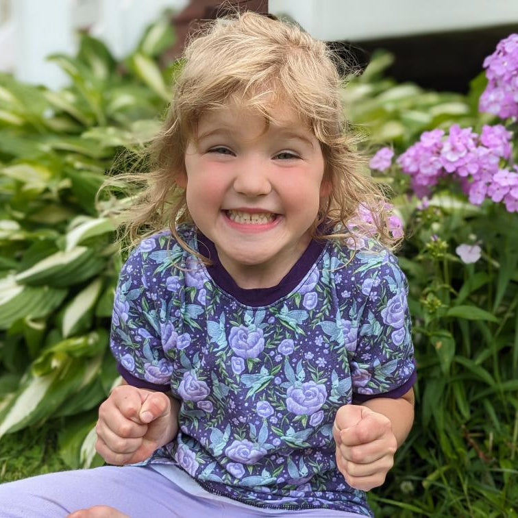 Child wearing a spooky purple floral shirt sitting, handmade