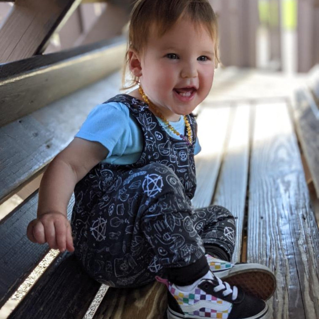 Spooky cute baby girl wearing a black romper with gothic designs in white