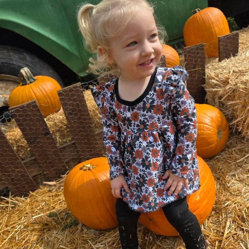 Child in a spooky floral peplum top with ruffles. Top is handmade for spooky kids. 