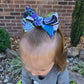 Child with a large hair bow outdoors on a brick wall background