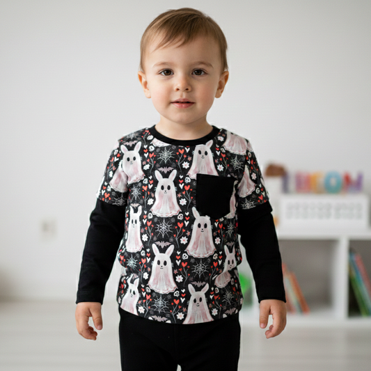 Child wearing a black long-sleeve shirt with white bunny patterns in a room.