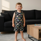 Child wearing a colorful patterned tank top and matching shorts standing in a living room.