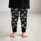 Child wearing black leggings with a colorful alien pattern on a light wooden floor.