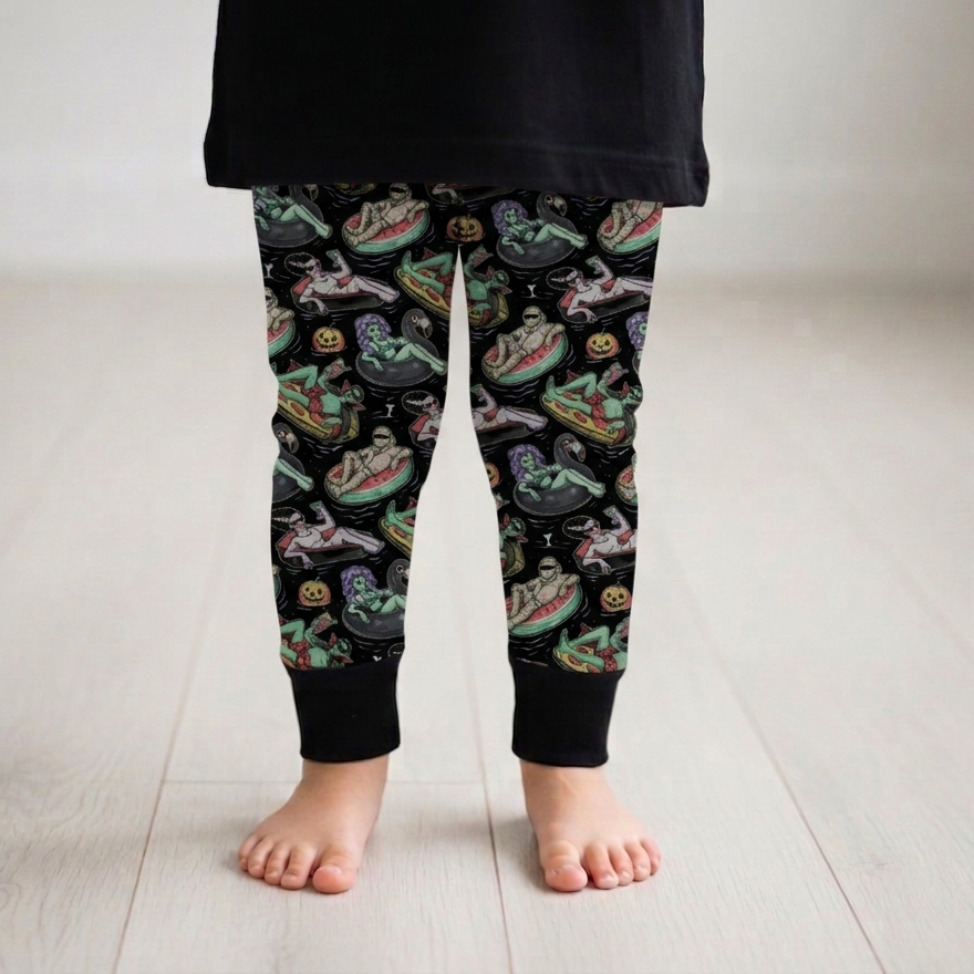 Child wearing black leggings with a colorful alien pattern on a light wooden floor.