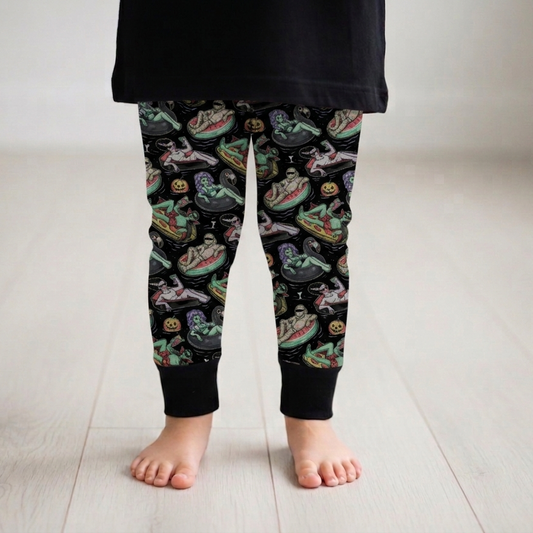 Child wearing black leggings with a colorful alien pattern on a light wooden floor.