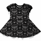 Goh baby, toddler or youth dress, short sleeves, black with white pattern. 
The print features dead head moth, moons, spiderwebs, roses and bones. 