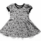 Spooky cute dress, black and white patterned. The print is white with black bats, spiderwebs, moons, leaves, and candies. 