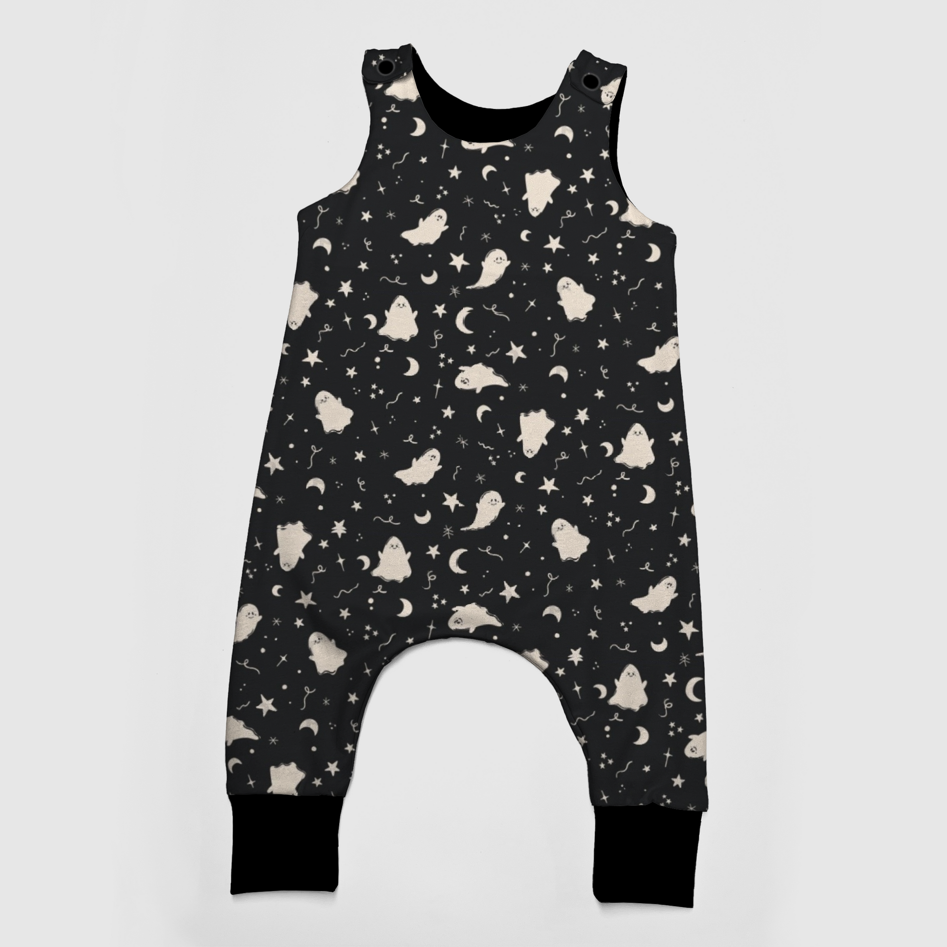Black baby overalls with white patterns featuring ghosts, stars and moons. 