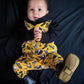 Metal - rock baby wearing a handmade romper with a rock n roll print on it. Yellow, black, white. With Boots. 