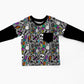 A toddler's long-sleeve shirt with a black crew neck and black sleeves, featuring a gray body with a colorful Halloween-themed pattern of ghosts, skulls, and lightning bolts.